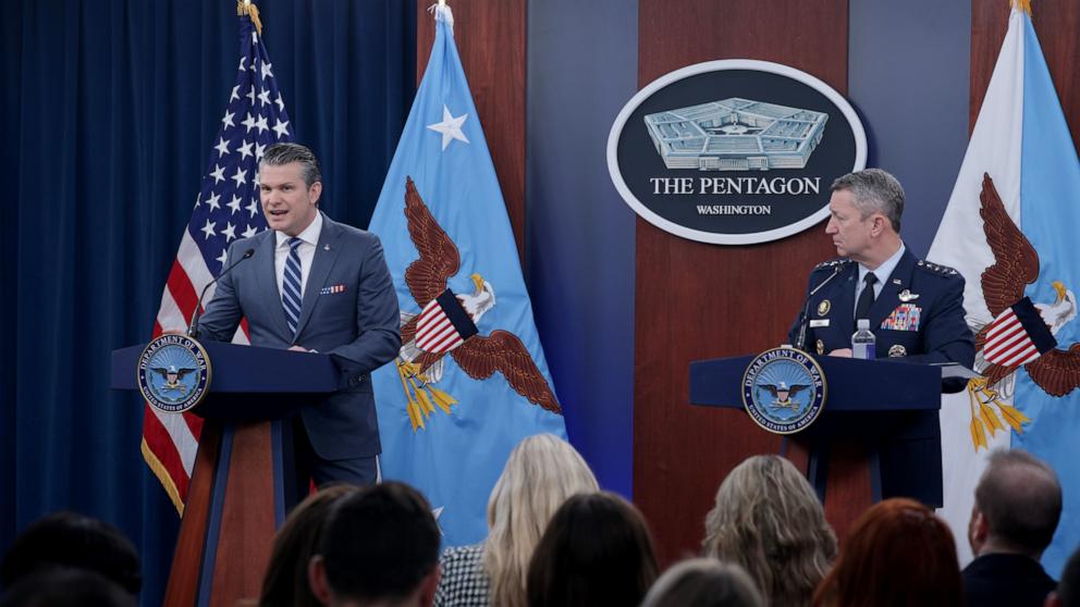 PHOTO: Secretary of War Pete Hegseth speaks as Chairman of the Joint Chiefs of Staff Gen. Dan Caine listens during a press briefing at the Pentagon, April 16, 2026 in Arlington, Virginia. 