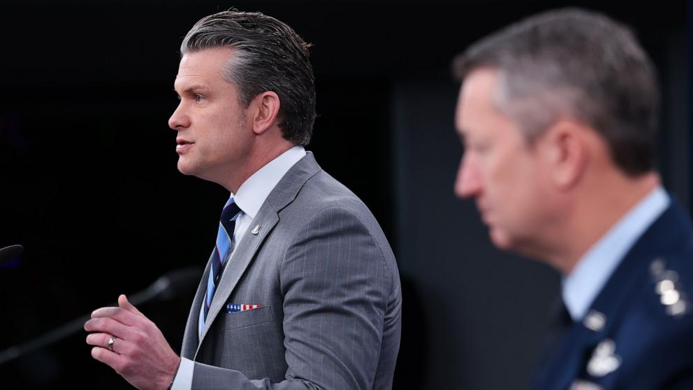 PHOTO: Secretary of War Pete Hegseth speaks as Chairman of the Joint Chiefs of Staff Gen. Dan Caine listens during a press briefing at the Pentagon, April 24, 2026 in Arlington, Virginia.