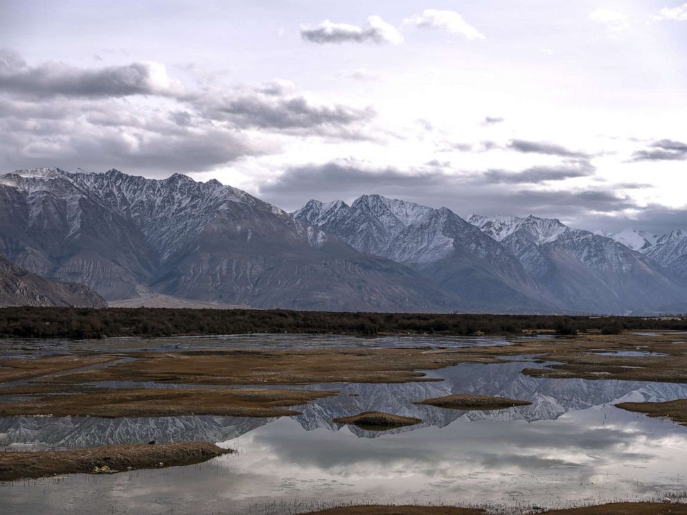 PHOTO: Mountains are reflected in water where the Nubra river flows into the Shyok river as part of the Indus River system, that separates the Ladakh and Karakaoram ranges in Nubra, Jamma and Kashmir, India, Nov. 14, 2019.