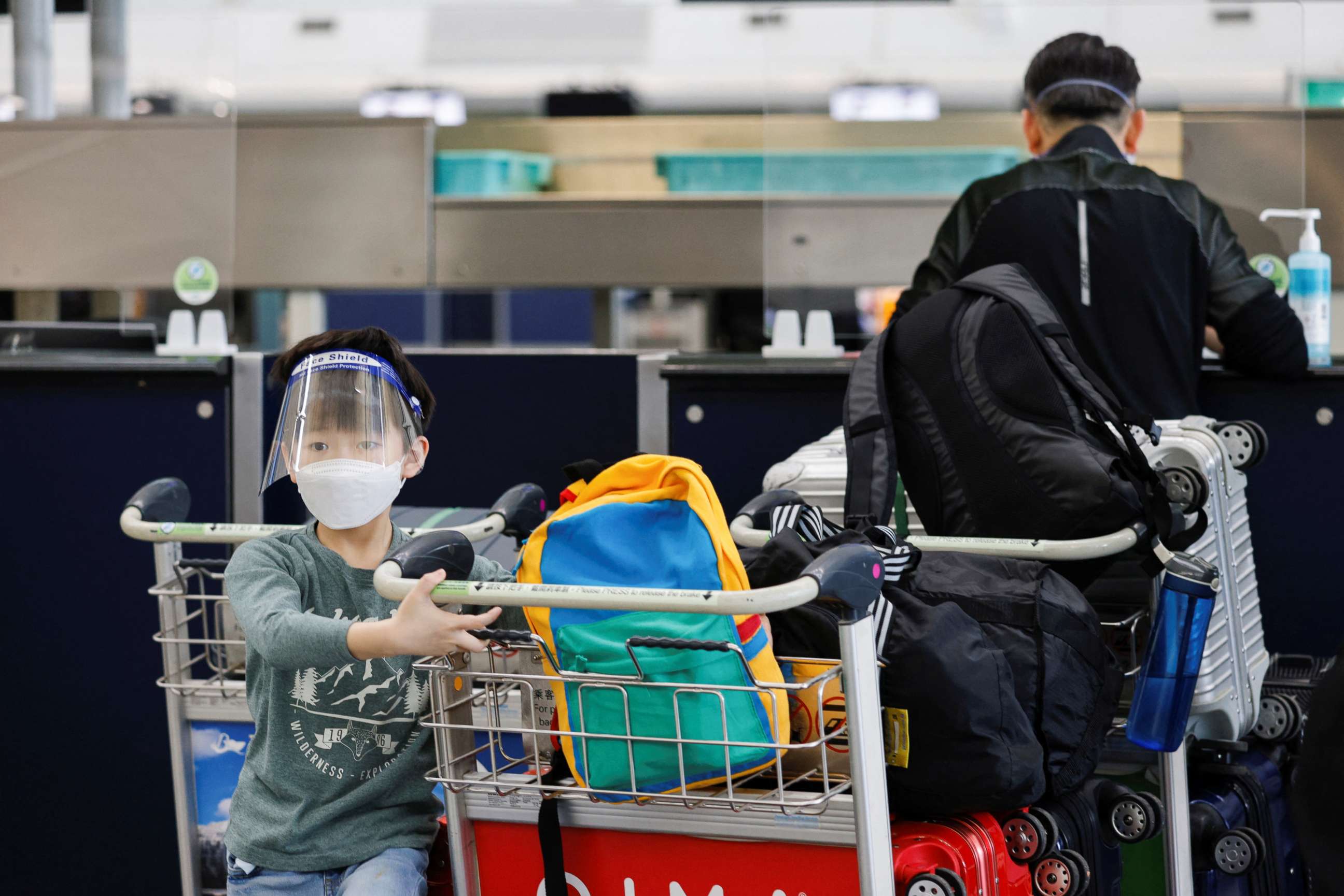PHOTO: A child wearing a face mask looks on at the check-in counters of the Hong Kong International Airport amid the COVID-19 pandemic in Hong Kong, China, March 21, 2022.