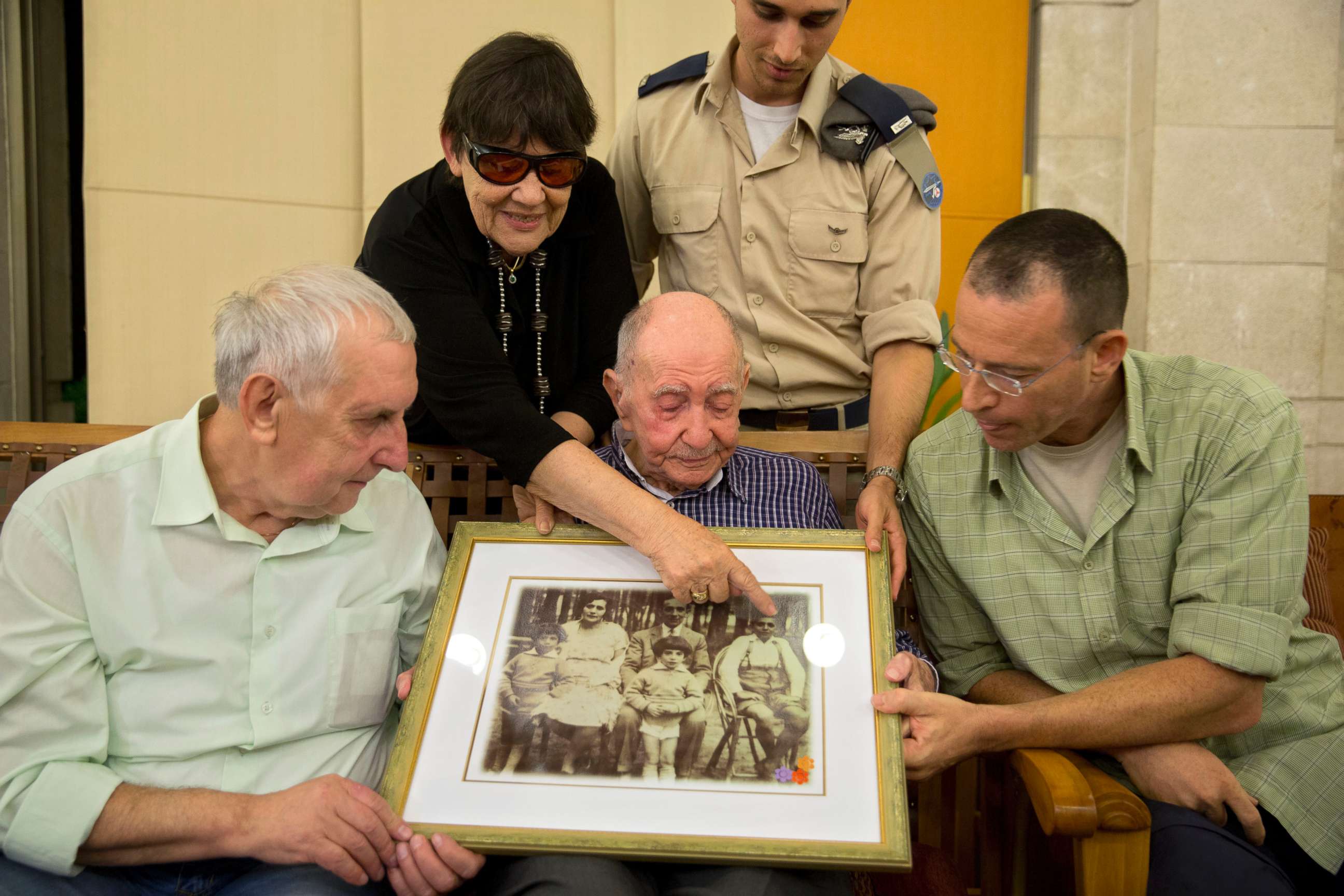 PHOTO: Israeli Holocaust survivor Eliahu Pietruszka, center, looks at a picture with Alexandre Pietruszka and family in the central Israeli city of Kfar Saba, Israel, Nov. 16, 2017.