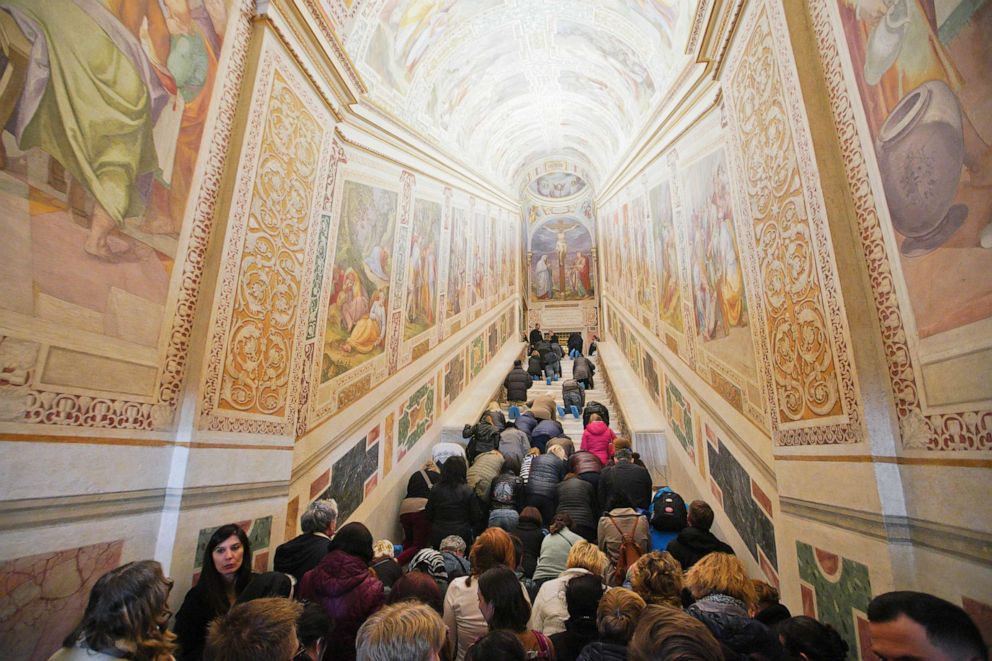  Faithful kneel on the newly restored Holy Stairs during a special opening, in Rome, Thursday, April 11, 2019.
					