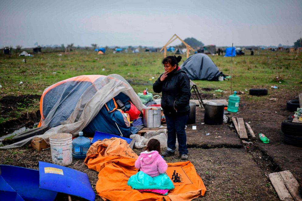 PHOTO: A woman and a girl are seen next to a tent set up in land occupied by homeless people outside Guernica, south of Argentina's capital, on Aug. 28, 2020, amid rising poverty in an economic crisis exacerbated by the coronavirus pandemic.