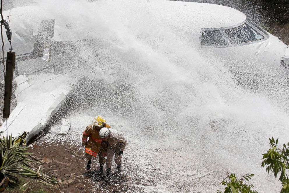 PHOTO: Firefighters take cover from firefighting foam applied onto the wreckage of a Gulfstream G200 aircraft that skidded off the runway during landing at Toncontin International Airport in Tegucigalpa, Honduras, May 22, 2018.