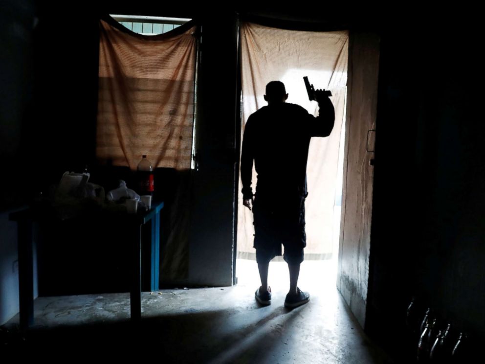PHOTO: A member of MS-13 street gang looks out from a house as police patrol the street outside, in San Pedro Sula, Honduras Sept. 29, 2018.