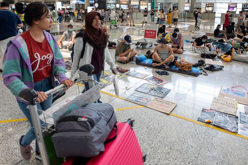 PHOTO: Passengers walk past anti-government protesters as they continue their sit-in at a designated protest area at Hong Kong Chek Lap Kok International Airport, in Hong Kong, China, August 14, 2019.