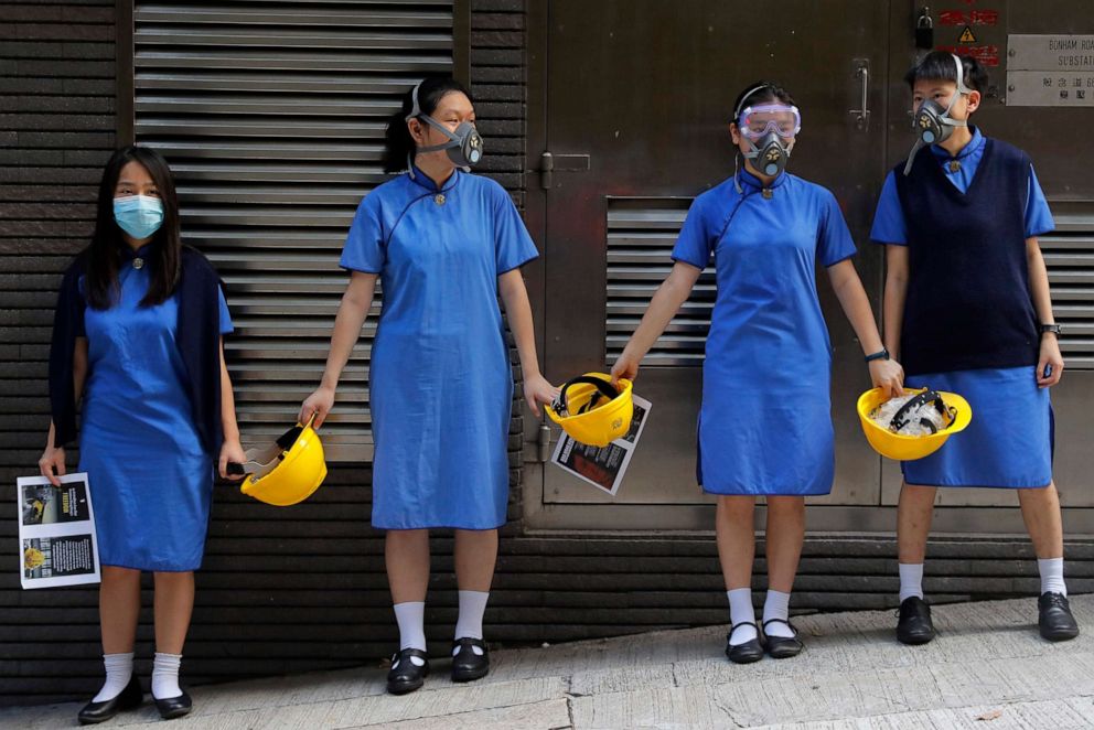 PHOTO: Students wearing masks hold hands while holding yellow helmets, a symbol of the pro-democracy protests, outside St. Stephen's Girls' College in Hong Kong, Sept. 9, 2019.