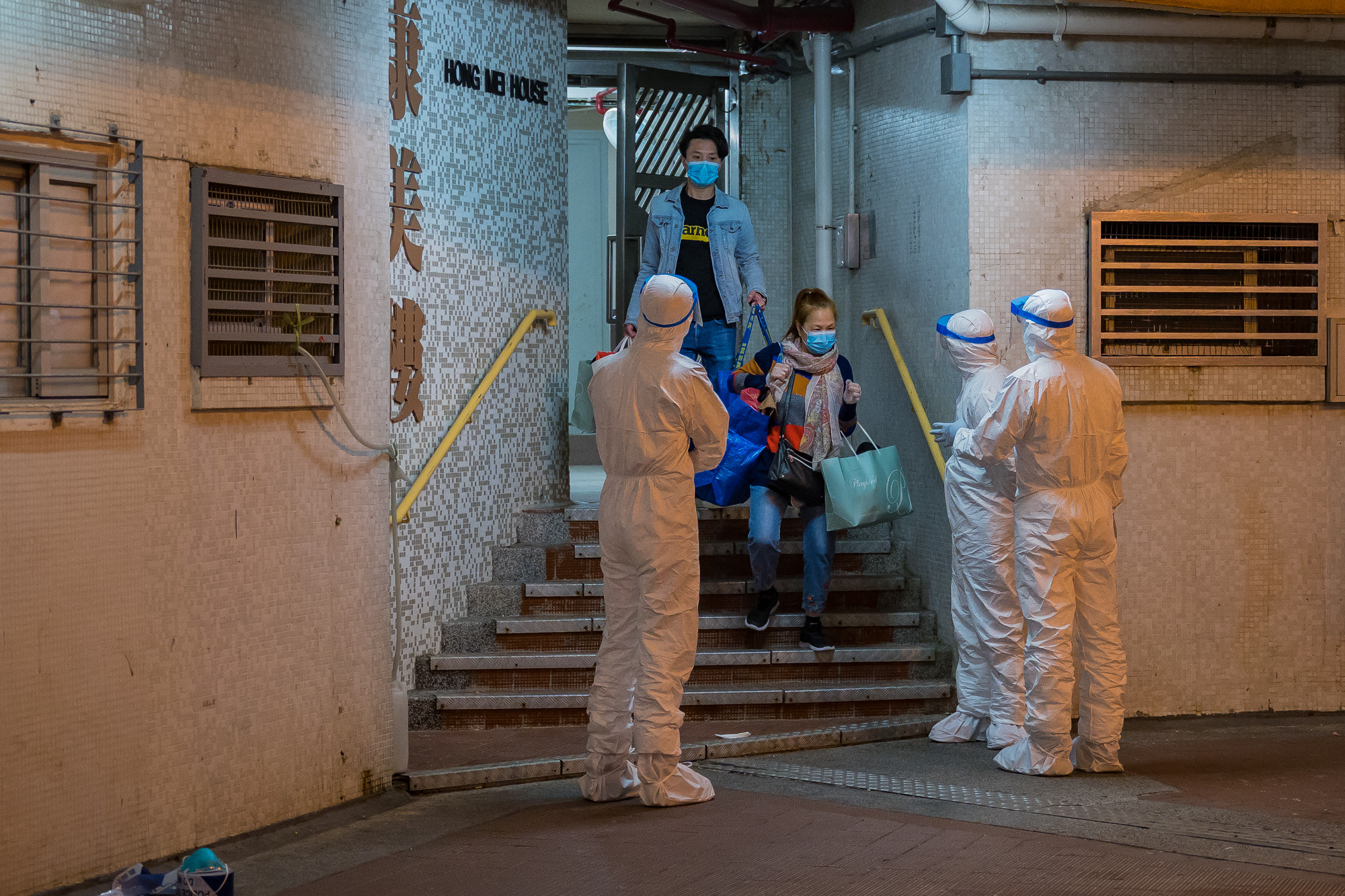 PHOTO: Residents leave the Hong Mei House residential building at Cheung Hong Estate as officials wearing protective gear stand guard outside the entrance, in Hong Kong's Tsing Yi area, China, on Feb. 11, 2020.