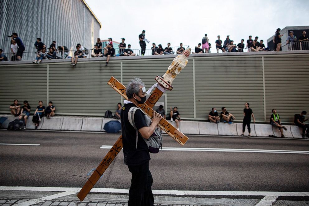 PHOTO: A man carries a cross as anti-extradition bill protesters gather on a road near West Kowloon railway station during a march in Hong Kong, China, July 07, 2019. 