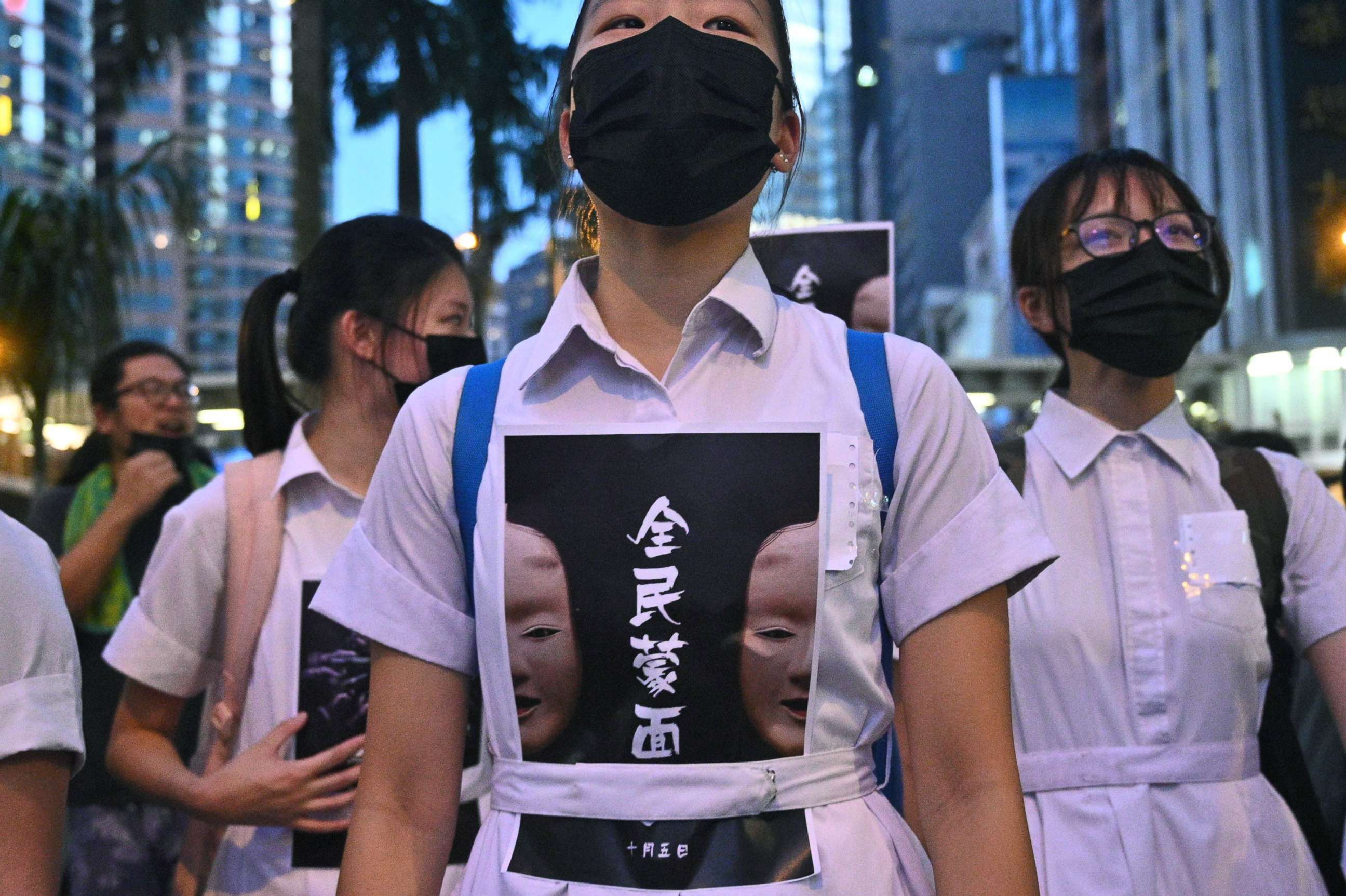 PHOTO: TOPSHOT - High school students chant slogans as they stick posters reading "all people masked" on their uniforms as protesters gather in Hong Kong, Oct. 4, 2019, after the government announced a ban on face masks.