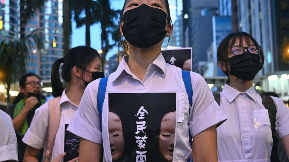 PHOTO: TOPSHOT - High school students chant slogans as they stick posters reading "all people masked" on their uniforms as protesters gather in Hong Kong, Oct. 4, 2019, after the government announced a ban on face masks.