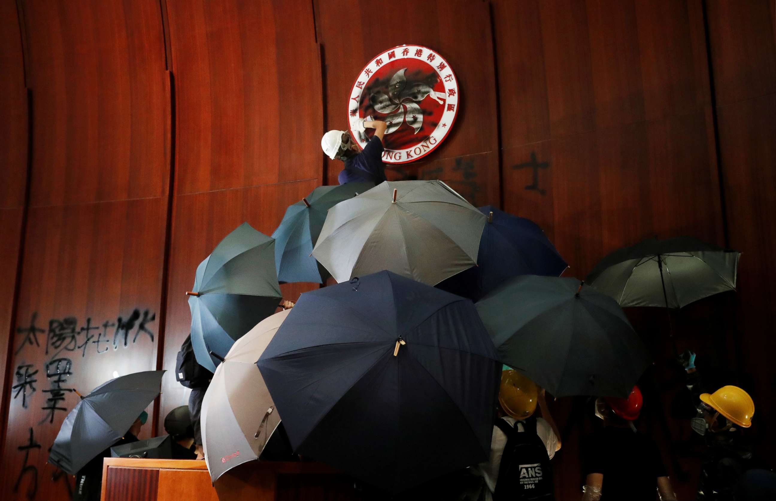 PHOTO: A person sprays paint over Hong Kong's coats of arms inside a chamber after protesters broke into the Legislative Council building during the anniversary of Hong Kong's handover to China in Hong Kong, July 1, 2019.