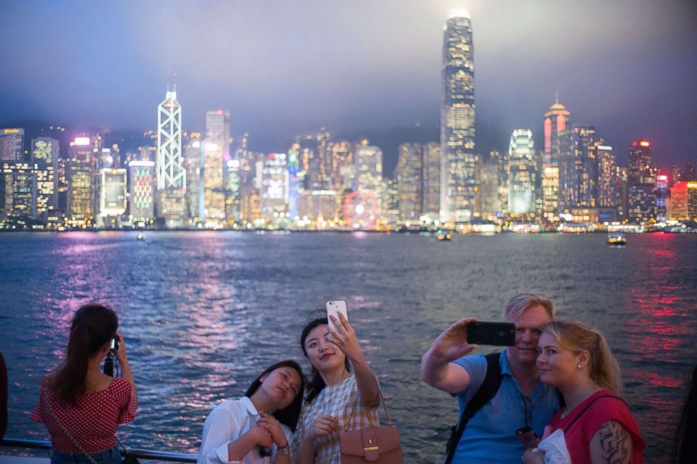   PHOTO: Tourists pose for selfies in front of a view of Victoria Harbor and the skyline of Hong Kong, May 7, 2018. 