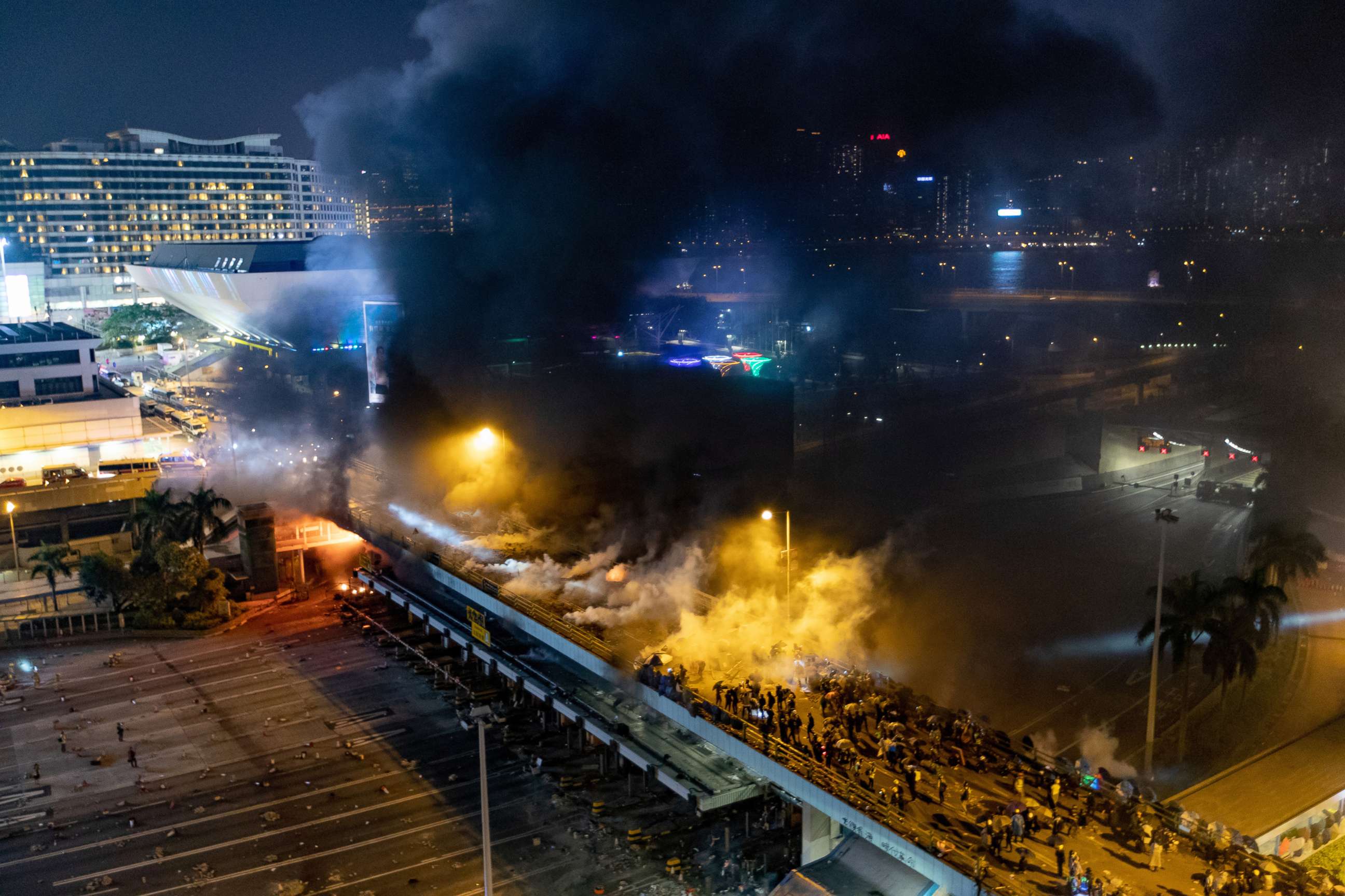 PHOTO: A huge cloud of smoke from an explosion rises over the footbridge on the drive way in front of Hong Kong Coliseum and Hong Kong harbor during the siege of Polytechnic University, Nov. 18, 2019.