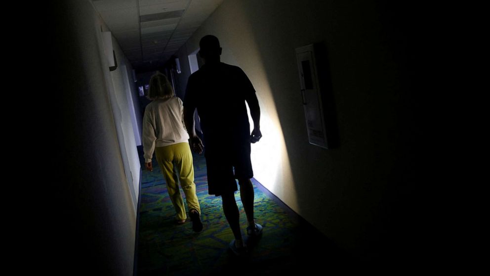 PHOTO: People walk in a hallway using a flashlight during a power outage as Hurricane Ian makes landfall in southwestern Florida, in Fort Myers, Fla., Sept. 28, 2022.