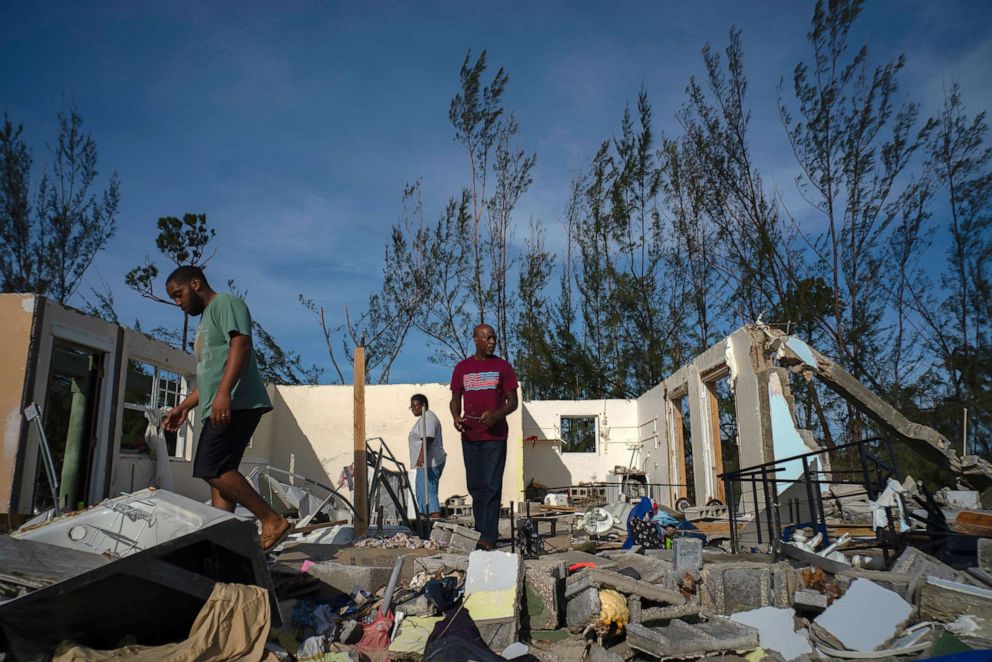 PHOTO: George Bolter, left, and his parents walk through the remains of his home destroyed by Hurricane Dorian in the Pine Bay neighborhood of Freeport, Bahamas, Wednesday, Sept. 4, 2019.