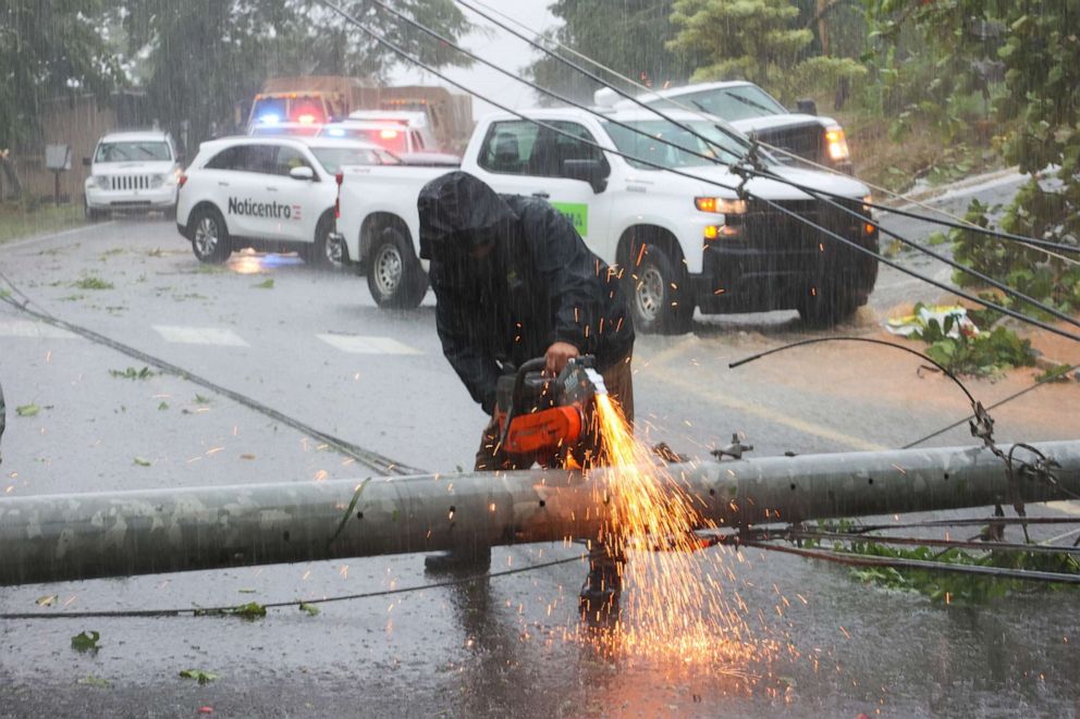PHOTO: A worker cuts an electricity pole that was downed by Hurricane Fiona as it blocks a road in Cayey, Puerto Rico, on Sept. 18, 2022.
