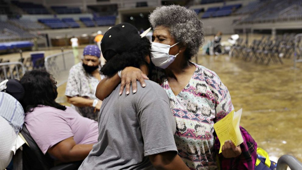 PHOTO: Demeteri Bushnell gets a hug from her great niece as they and other evacuees prepare to board a bus as they are evacuated by local and state government officials before the arrival of Hurricane Laura, on Aug. 26, 2020, in Lake Charles, Louisiana.