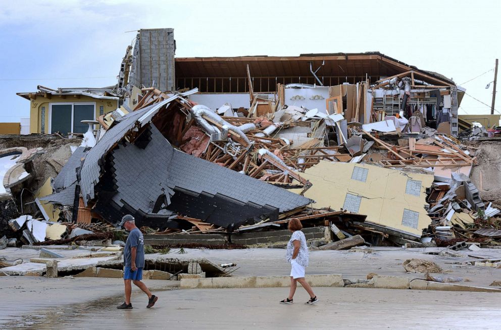 PHOTO: People walk past a home that collapsed onto the beach due to the storm surge and resulting erosion caused by Hurricane Nicole on November 11, 2022 in Wilbur-By-The-Sea, Florida.