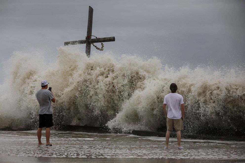 PHOTO: Mark Allums, left, and Hunter Clark watch waves crash ashore as outer bands from Hurricane Laura begin to hit the coast, Aug. 26, 2020, in High Island, Texas.