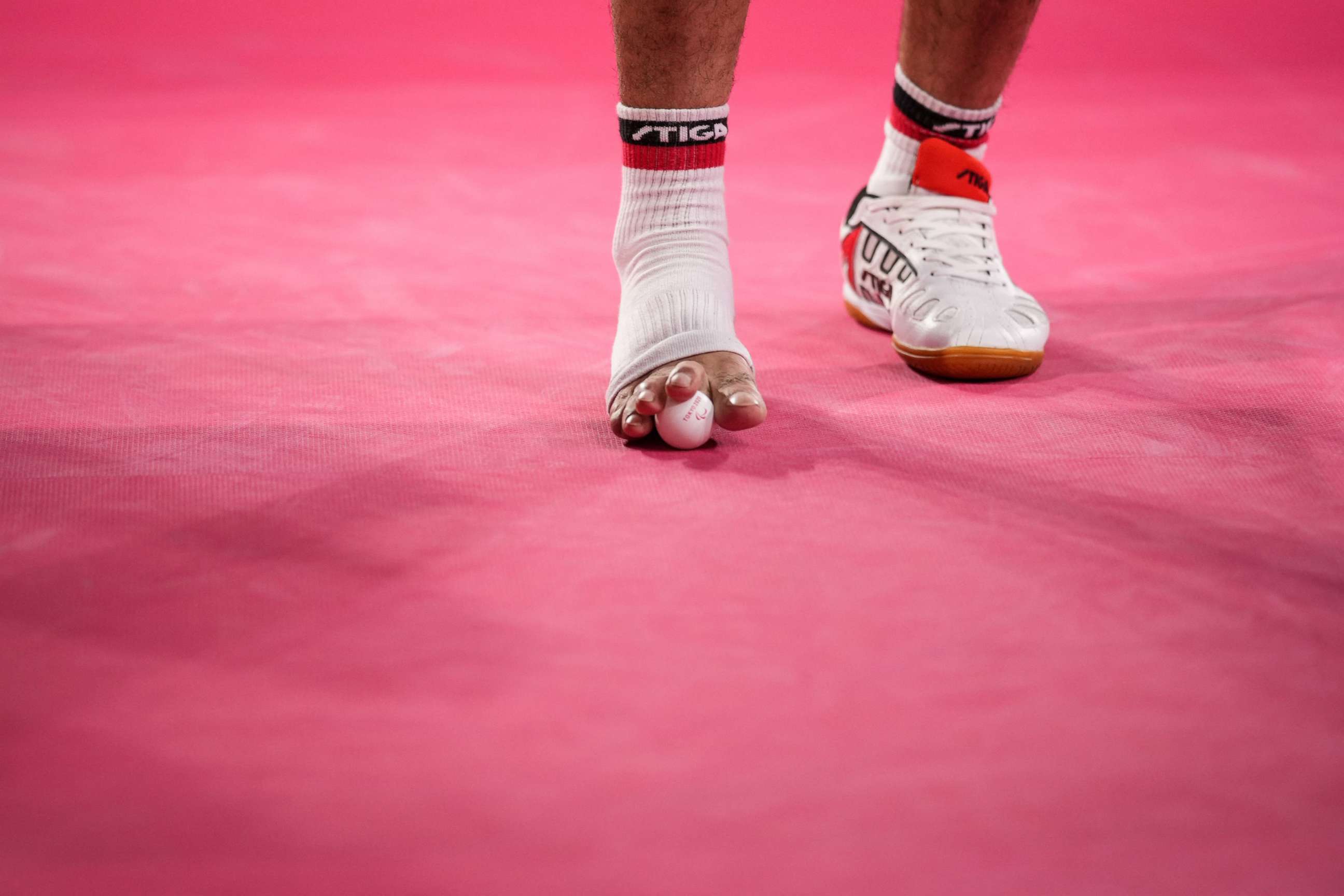 PHOTO: Ibrahim Elhusseiny Hamadtou grabs a ball on a floor to serve during the men's table tennis singles (Class 6) Group match against China's Chao Chen at the Paralympic Games at Tokyo Metropolitan Gymnasium in Tokyo on Aug. 27, 2021.