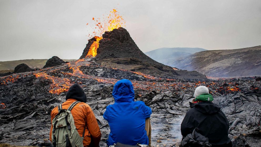 PHOTO: Hikers look at the lava flowing from the erupting Fagradalsfjall volcano near Reykjavik, Iceland, March 21, 2021.