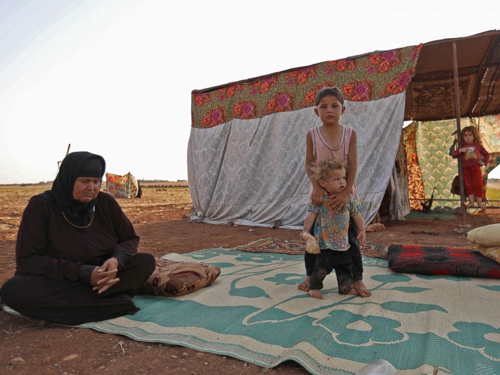 PHOTO: A Syrian woman sits on a straw mat next to children outside a tent at a camp for displaced civilians fleeing from advancing government forces near the village of Sarman in the rebel-held northwestern Idlib province, Sept. 1, 2018.