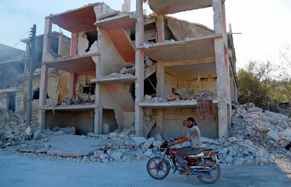 PHOTO: A Syrian man rides a motorcycle past a destroyed building in an area that was hit by a reported air strike in the district of Jisr al-Shughur, in the Idlib province, on Sept. 4, 2018.