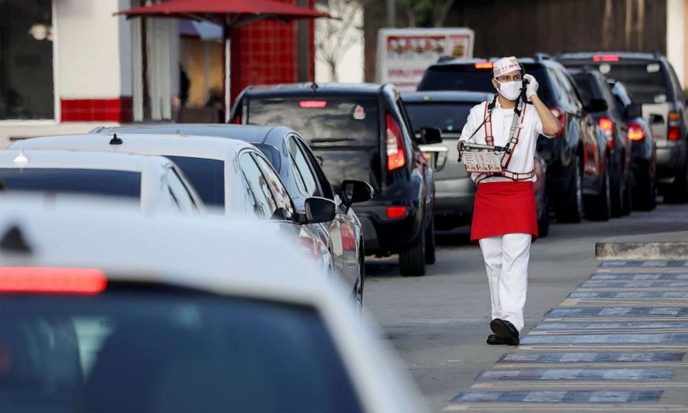 PHOTO: An employee wears a face covering while taking orders from motorists in the drive-through lane at an In-N-Out Burger restaurant amid the COVID-19 pandemic in Los Angeles, on July 1, 2020.