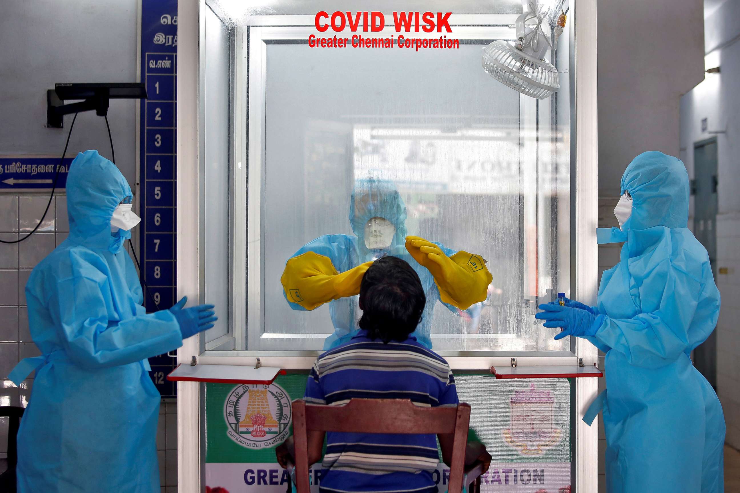 PHOTO: A doctor in a protective chamber takes a swab from a man to test for coronavirus disease (COVID-19) at a newly installed Walk-In Sample Kiosk (WISK) in a government-run hospital in Chennai, India, April 13, 2020. 