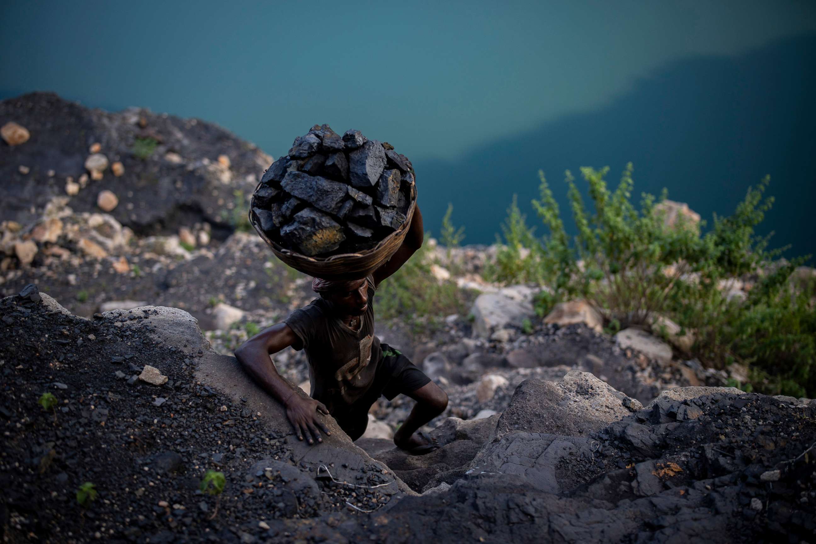 PHOTO: A man climbs a steep ridge with a basket of coal scavenged from a mine near Dhanbad, an eastern Indian city in Jharkhand state, Sept. 24, 2021.