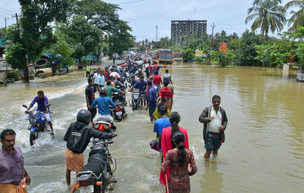 PHOTO: People move past a flooded road in Thrissur, in Kerala, India, Aug. 17, 2018.