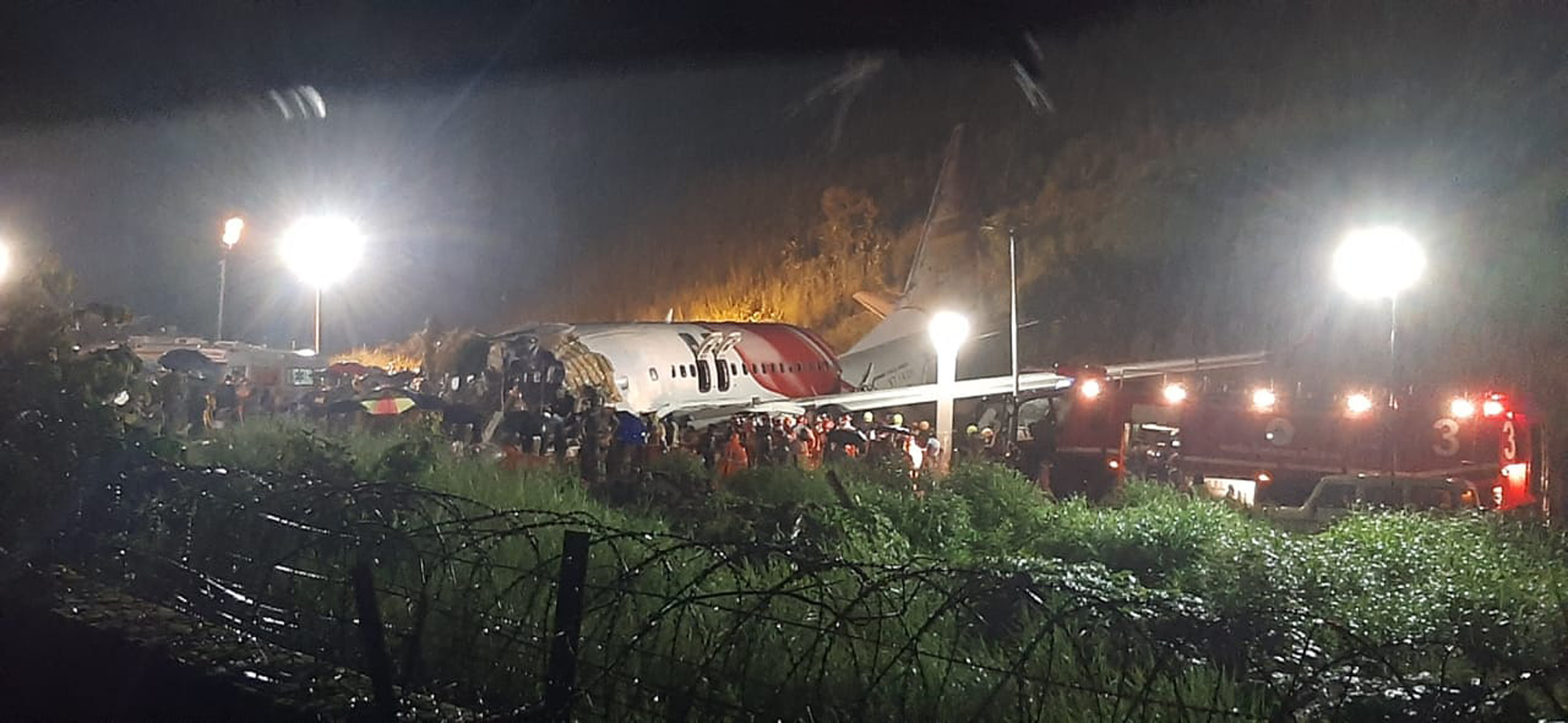 PHOTO: People gather around an Air India Express flight that skidded off a runway while landing at the airport in Kozhikode, Kerala state, India, Aug. 7, 2020.