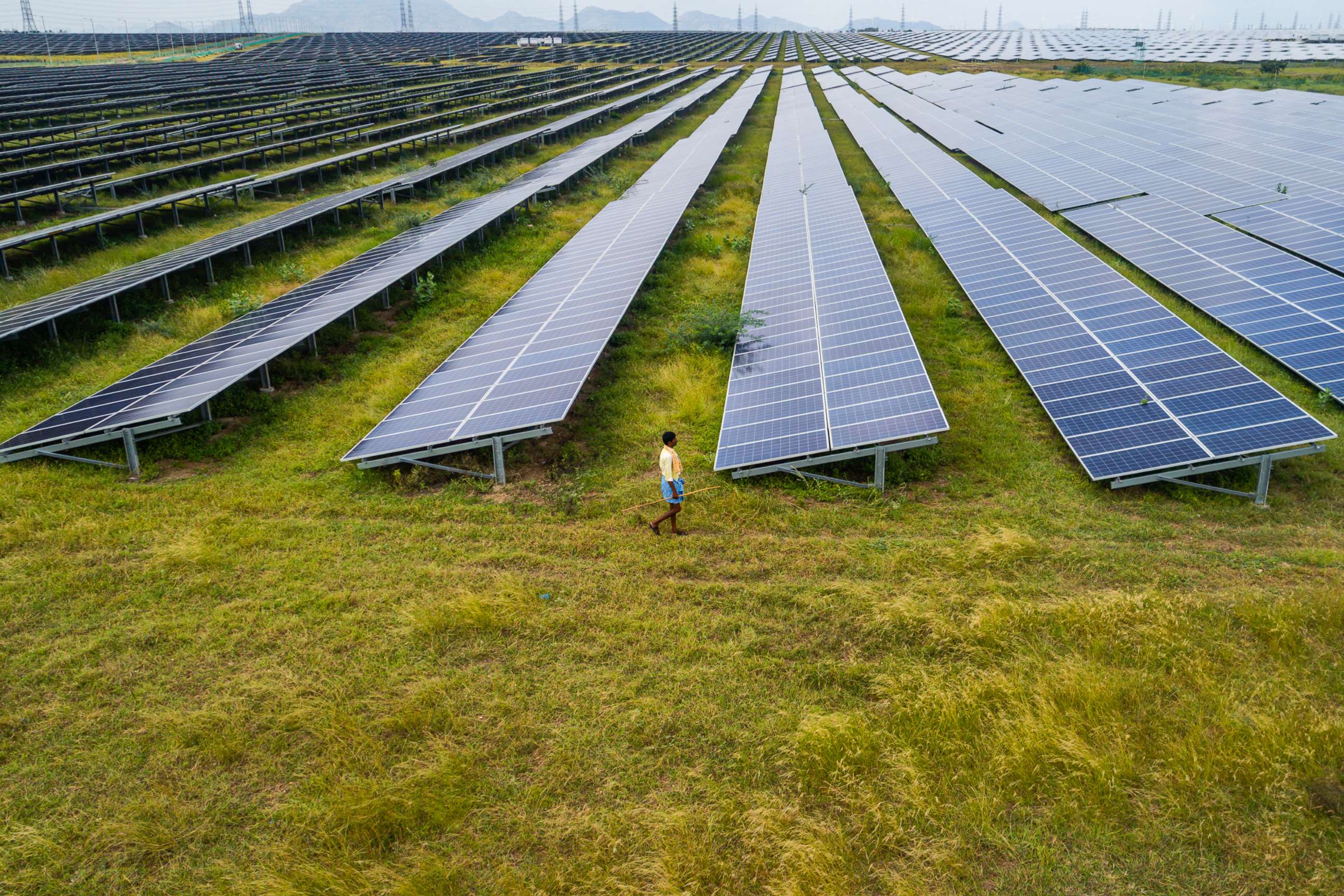 PHOTO: A man walks past photovoltaic cell solar panels in the Pavagada Solar Park, in Kyataganacharulu village, Karnataka, India, Oct. 11, 2021.