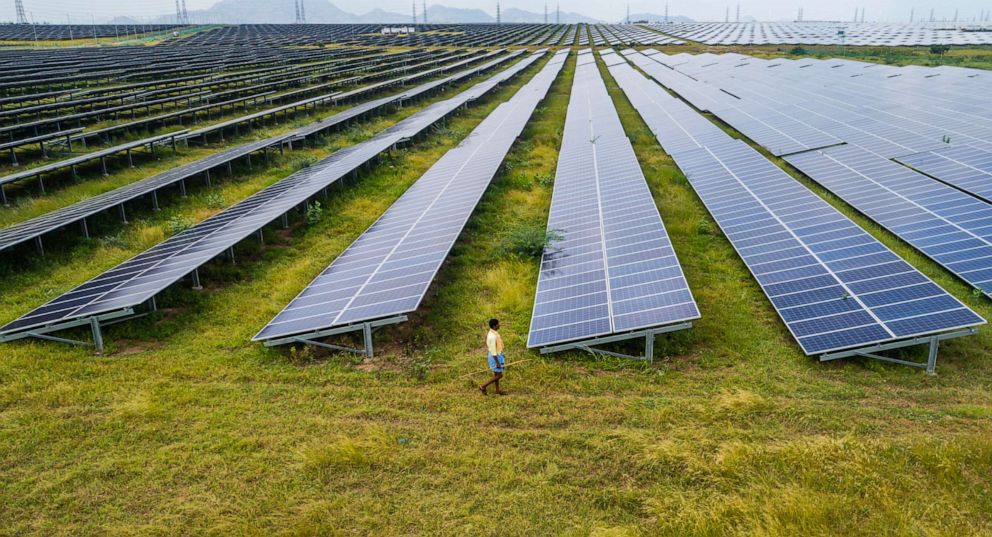 PHOTO: A man walks past photovoltaic cell solar panels in the Pavagada Solar Park, in Kyataganacharulu village, Karnataka, India, Oct. 11, 2021.