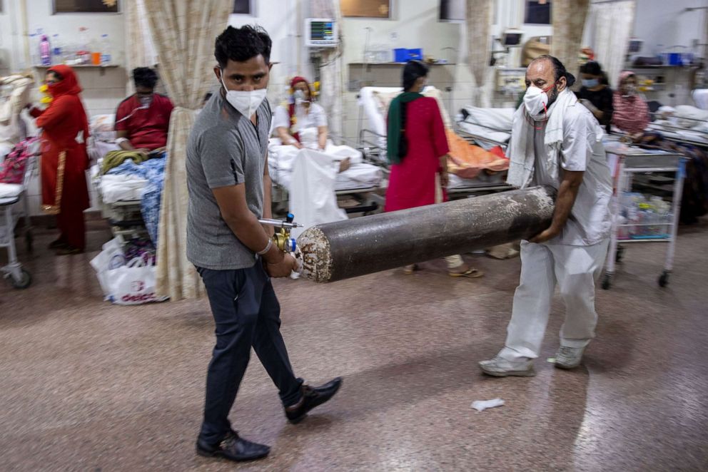 PHOTO: Relatives of a woman suffering from the coronavirus disease (COVID-19), carry an oxygen cylinder as she receives treatment in the emergency room of Holy Family Hospital in New Delhi, India, May 1, 2021.