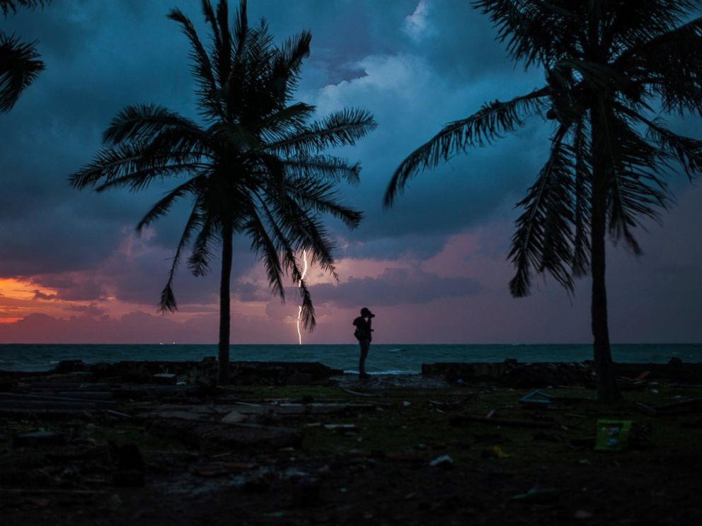 PHOTO: A photojournalist is silhouetted by the sunset as a lightning strike at a resort affected by Saturdays tsunami in Carita, Indonesia, Tuesday, Dec. 25, 2018.