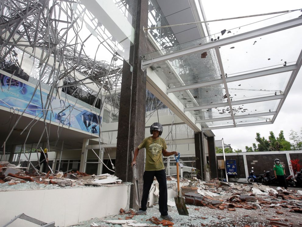 A man cleans up at a building damaged by an earthquake in Bali, Indonesia, Monday, Aug. 6, 2018.