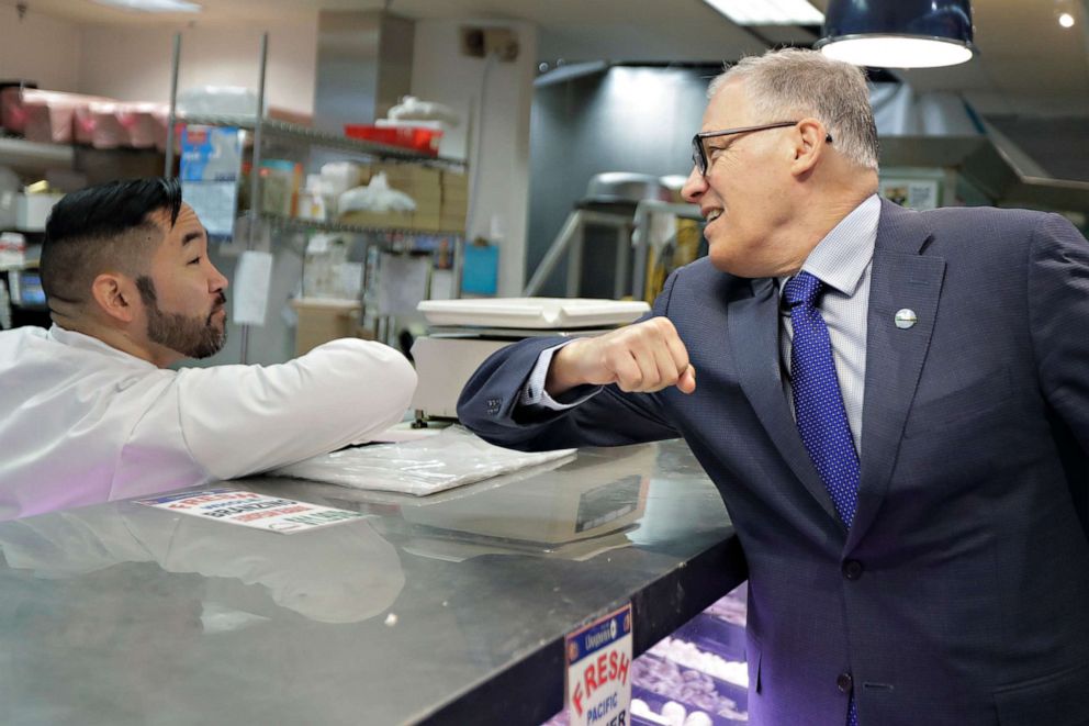 PHOTO: Washington Gov. Jay Inslee bumps elbows with a worker at the seafood counter of the Uwajimaya Asian Food and Gift Market, March 3, 2020, in Seattle's International District.