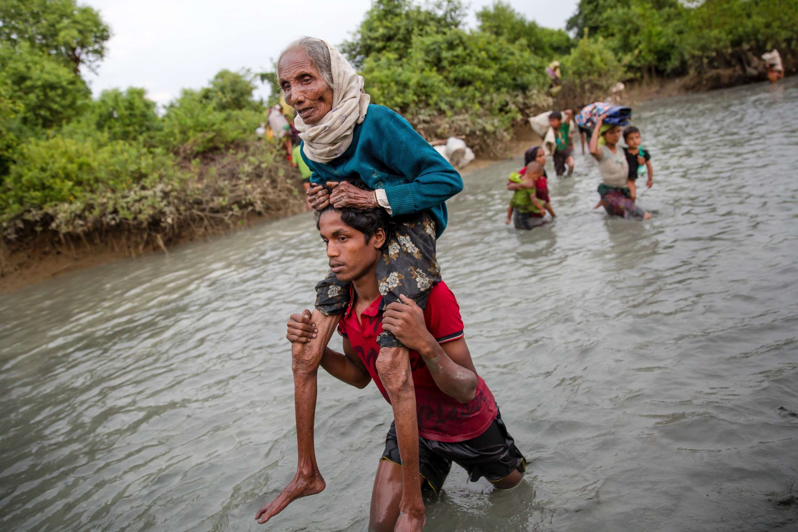 PHOTO:A Rohingya Muslim man carries an elderly woman through water after crossing the border from Myanmar into Bangladesh, near Palong Khali, Nov. 1, 2017. 