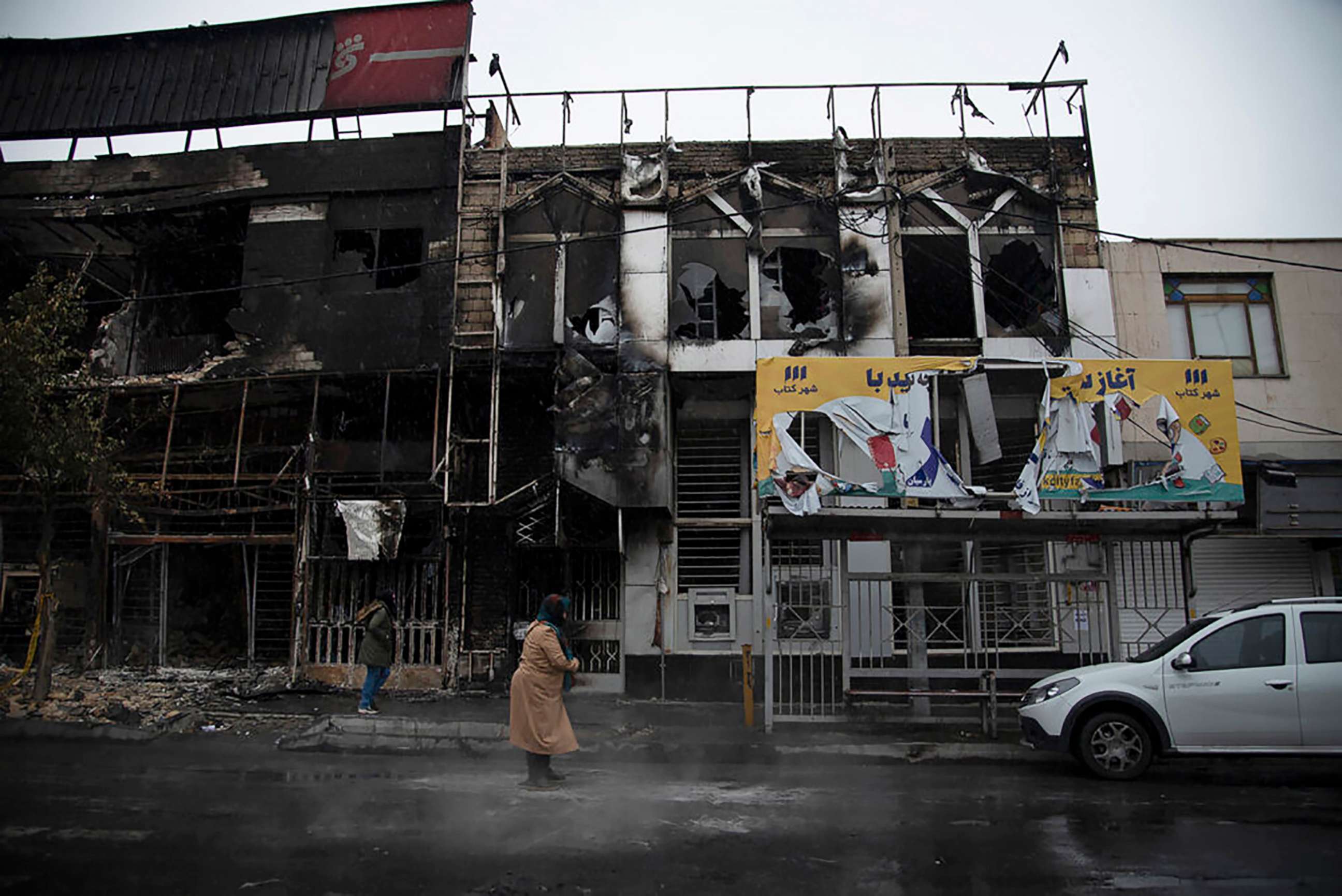 PHOTO: People walk past buildings which burned during protests that followed the rise of gasoline prices, in the city of Karaj, west of Tehran, Iran, Nov. 18, 2019, in a photo released by Iranian Students' News Agency, ISNA.