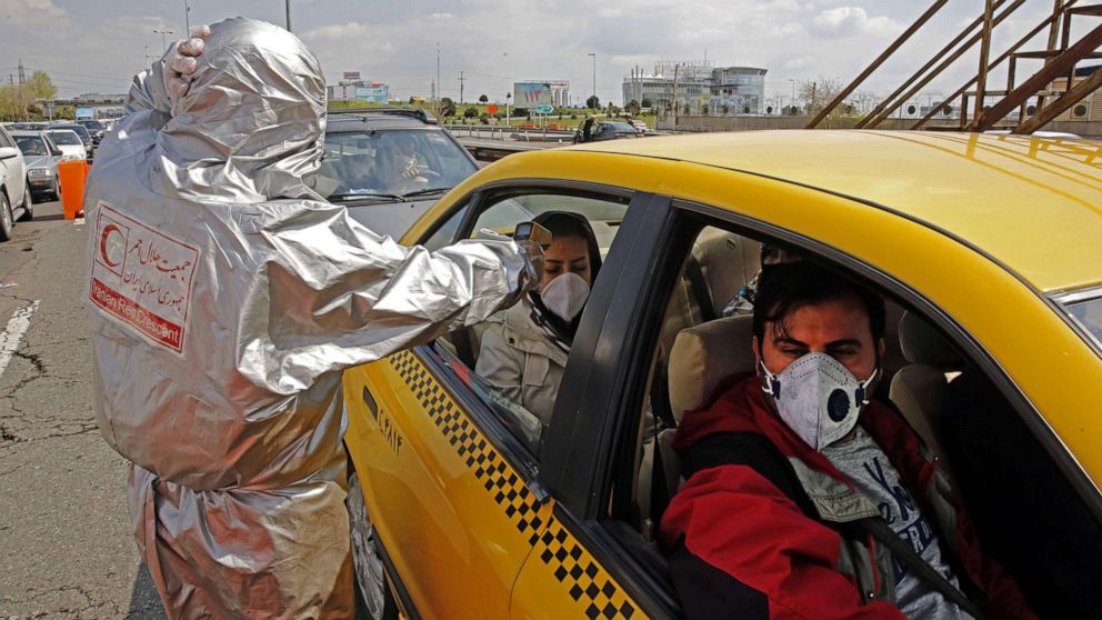 PHOTO: Members of Iranian Red Crescent test people with possible coronavirus COVID-19 symptoms, as police blocked Tehran to Alborz highway to check every car following ordered by the Iranian government, outside Tehran on March 26, 2020. 