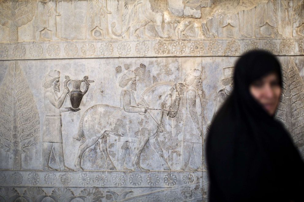 PHOTO: An Iranian woman walks past Achaemenid figuers carved on the wall of the eastern stairway of the Apadana palace at the ruins of Persepolis near Shiraz in Iran on Sept. 26, 2014.