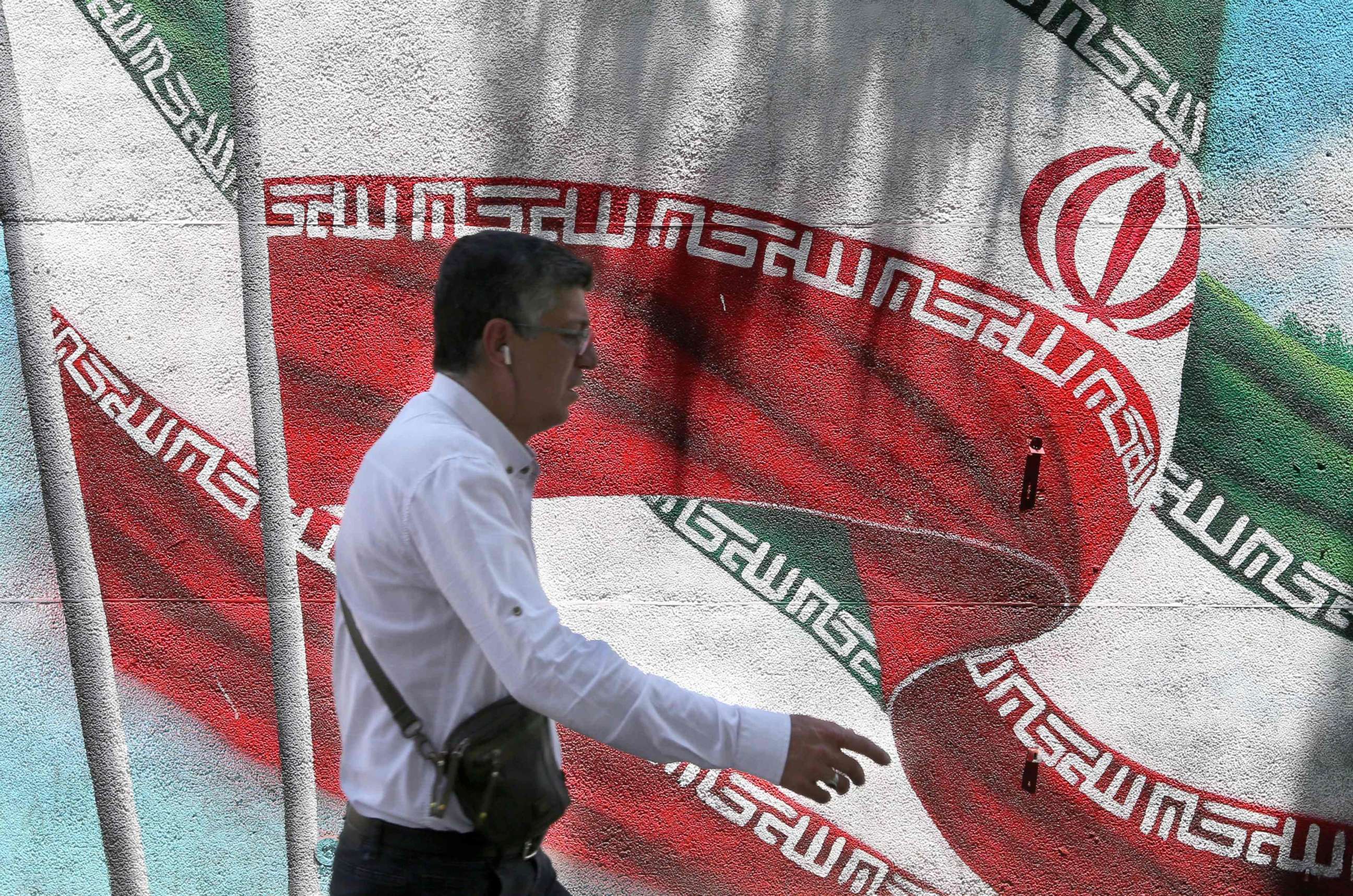 PHOTO: An Iranian man walks past a mural painted with the Iranian flag in Tehran on June 25, 2019. 