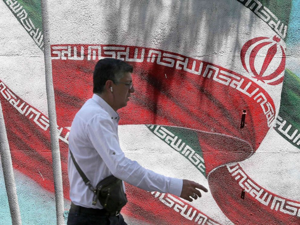 PHOTO: An Iranian man walks past a mural painted with the Iranian flag in Tehran on June 25, 2019.