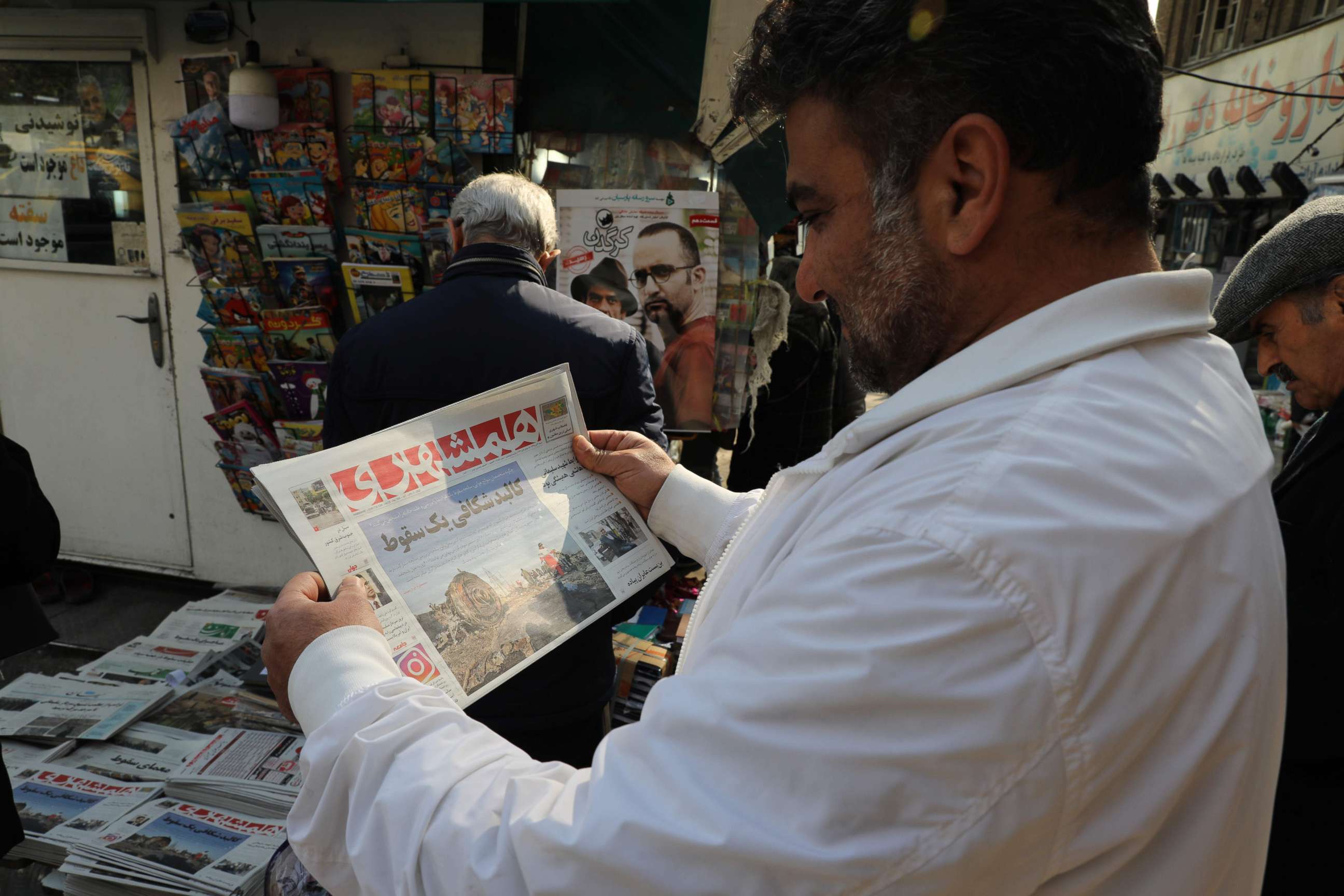 PHOTO: An Iranian holds a newspaper with a picture of the debris of the Ukrainian plane that crashed in Tehran earlier this week, outside a news stand in the Islamic republic's capital on January 11, 2020. 