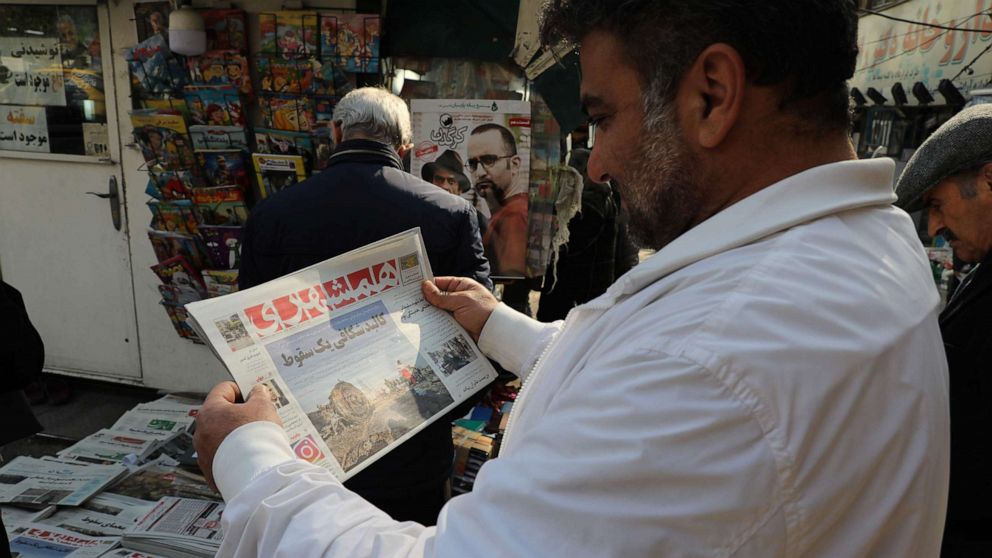 PHOTO: An Iranian holds a newspaper with a picture of the debris of the Ukrainian plane that crashed in Tehran earlier this week, outside a news stand in the Islamic republic's capital on January 11, 2020. 