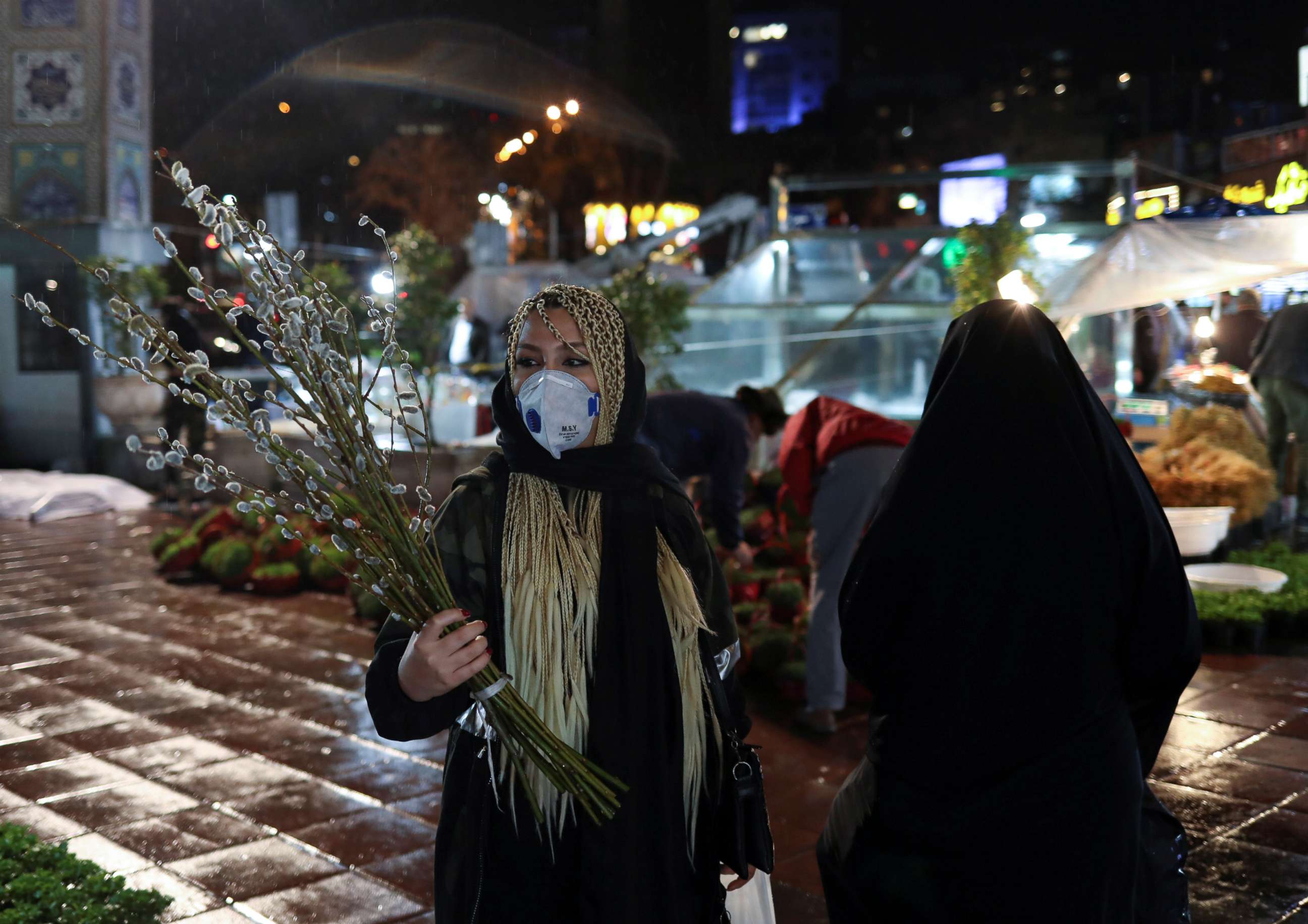 PHOTO: An Iranian woman wears a protective face mask, amid fear of COVID-19, as she carries catkins, ahead of the Iranian New Year Nowruz, on March 20, in Tajrish square northern Tehran, Iran on March 18, 2020. 