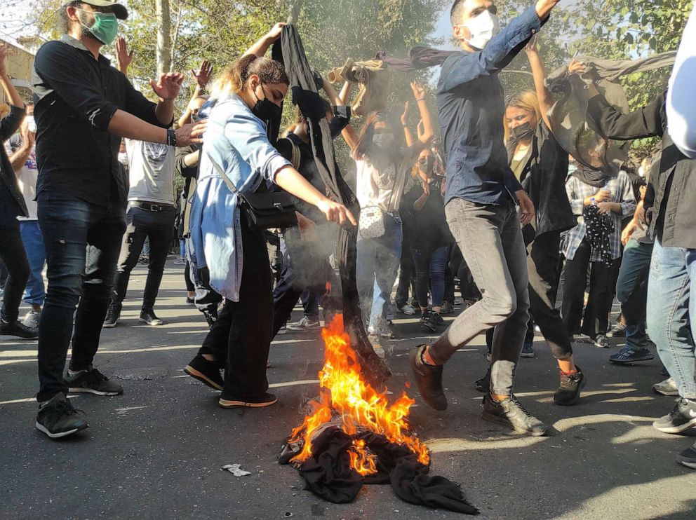 PHOTO: In this Oct. 1, 2022, file photo, Iranian protesters set their scarves on fire while marching down a street in Tehran, Iran.