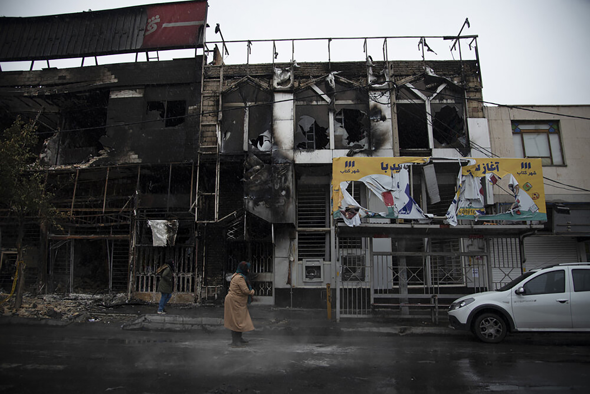 PHOTO: In this photo taken Nov. 18, 2019, and released by Iranian Students' News Agency, people walk past buildings which burned during protests that followed the authorities' decision to raise gasoline prices, in Karaj, west of the capital Tehran, Iran.